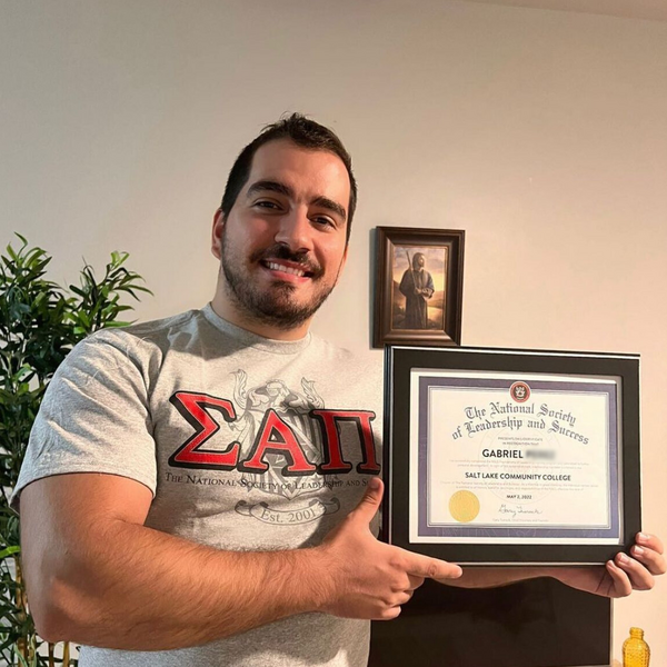 NSLS Member Holding Up His Induction Certificate.